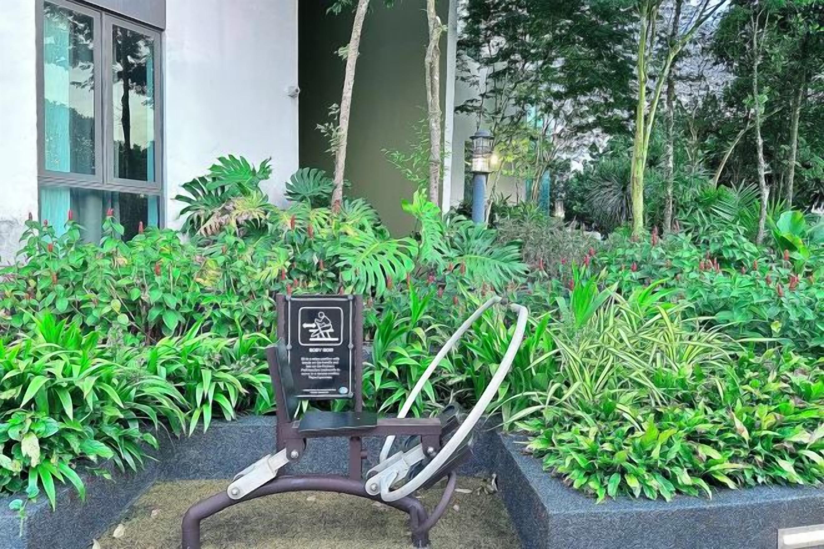 Ein Gartenbereich mit einer Bank, einem Schild und unterschiedlichen Pflanzen.