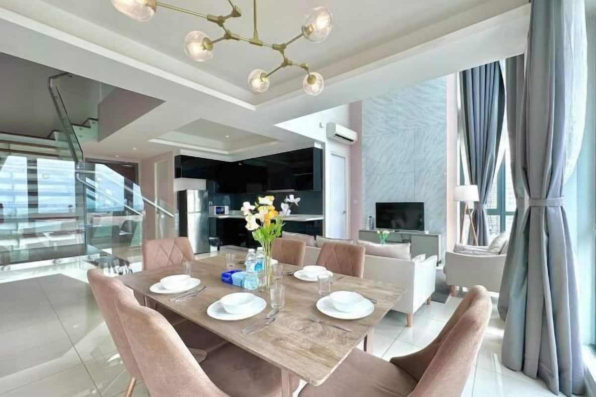 A modern dining area with a wooden table set for four, surrounded by cushioned chairs.