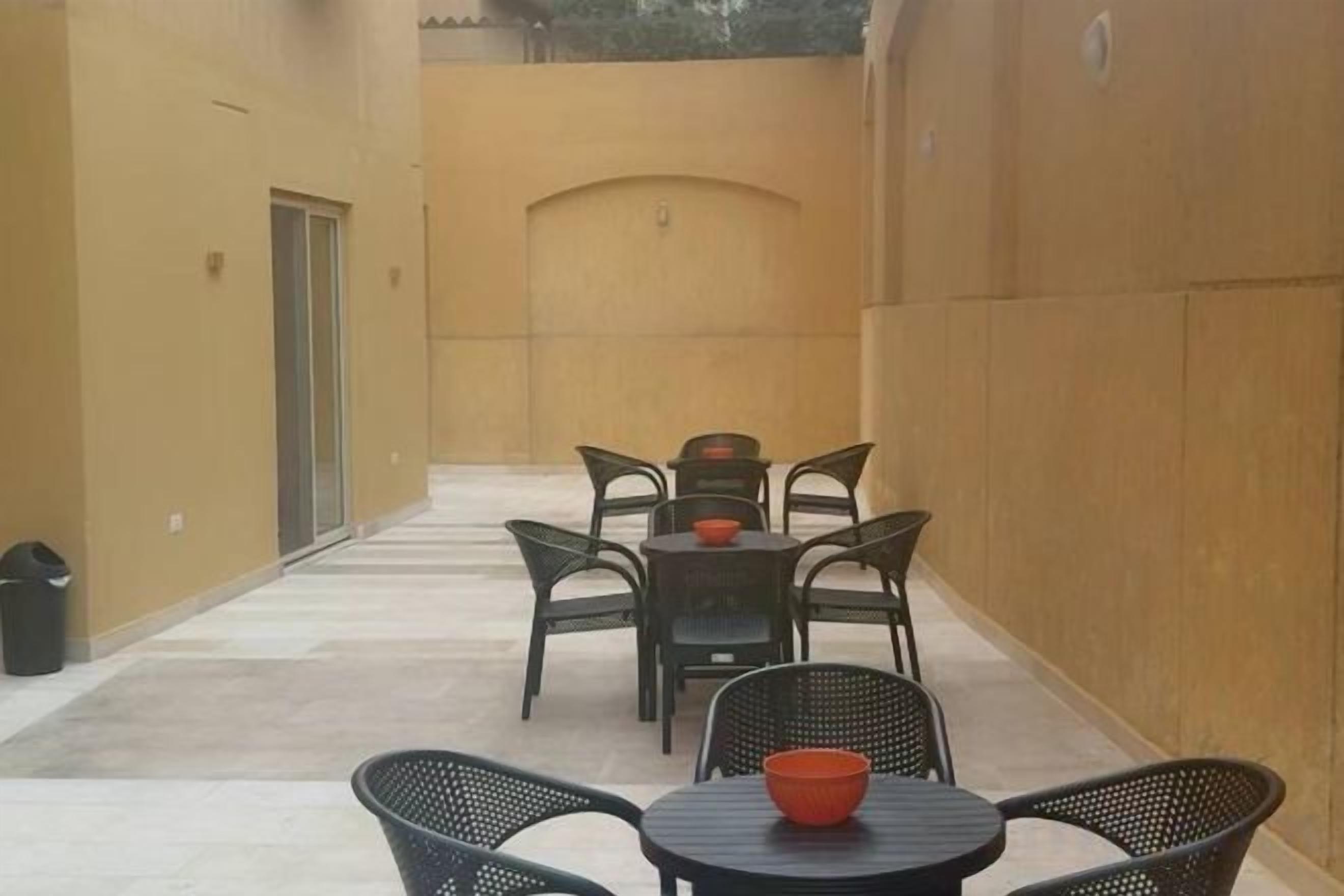 An outdoor patio area with a table and chairs, a trash bin, and a door.