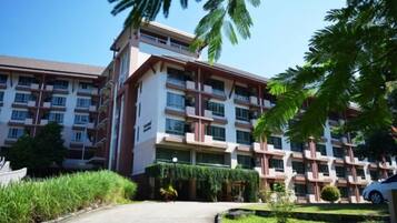 A multi-story hotel with a central courtyard, surrounded by greenery and palm trees.