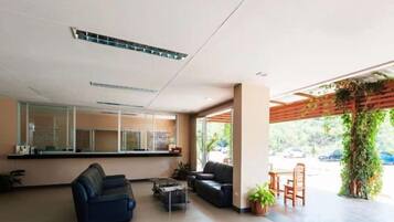 A modern lobby with a reception desk, seating area, and a view of the outdoors.