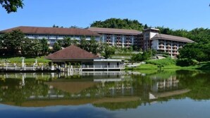 A hotel with a large building, a dock, and a lake. - Wanawes Mae Fah Luang (Chiang Rai)