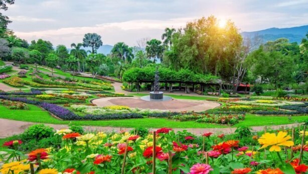 A well-maintained garden with various flower beds and a central statue. - Wanawes Mae Fah Luang (Chiang Rai)