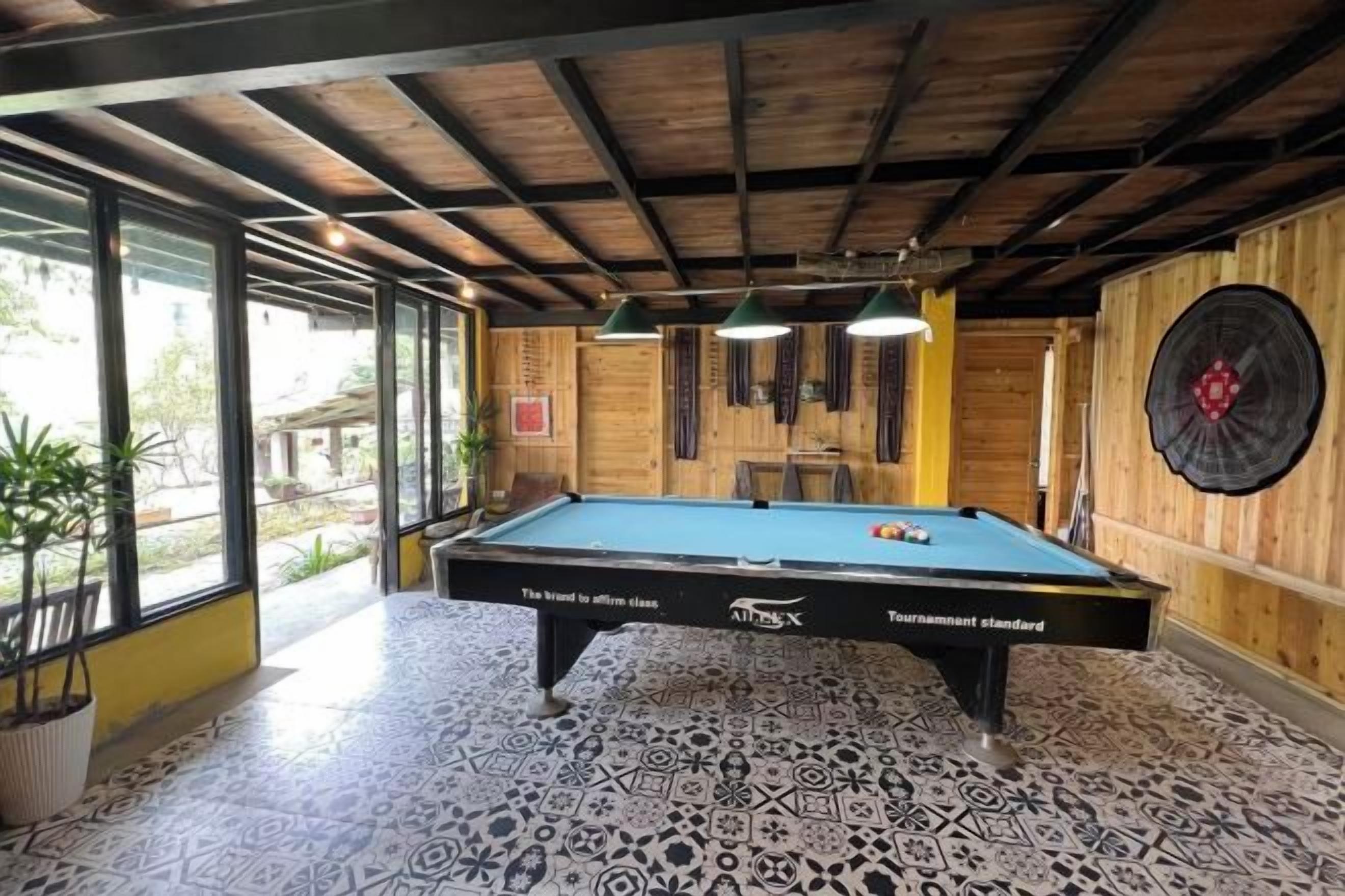 A pool table in a room with wooden walls and a patterned floor.