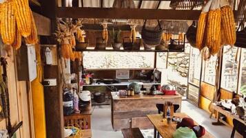 A rustic interior with a wooden counter, hanging baskets, and a view through a window.
