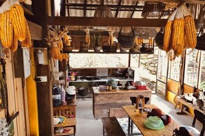 Un intérieur rustique avec un comptoir en bois, des paniers suspendus et une vue par la fenêtre.