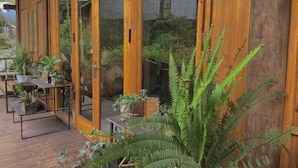 A wooden deck with potted plants and a large fern. - Sapa Ta Van Desi House - Mountain View & Hiking Tours (Sapa)