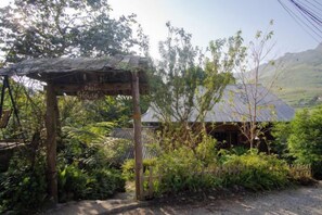 Una estructura de madera rústica con techo de metal, identificada como 'Guest House', rodeada de abundante vegetación y un paisaje montañoso.