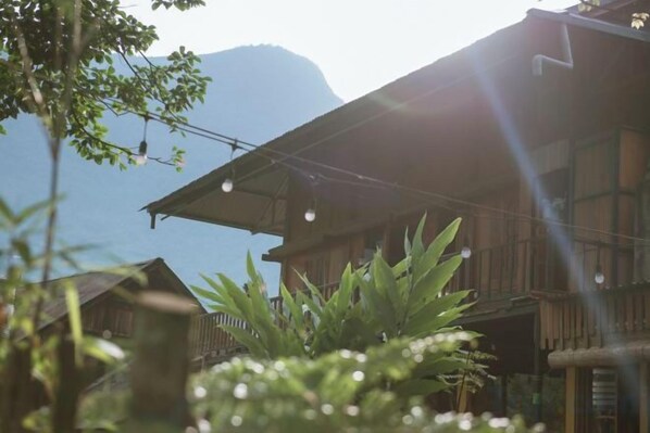 A wooden building with balconies, surrounded by greenery.