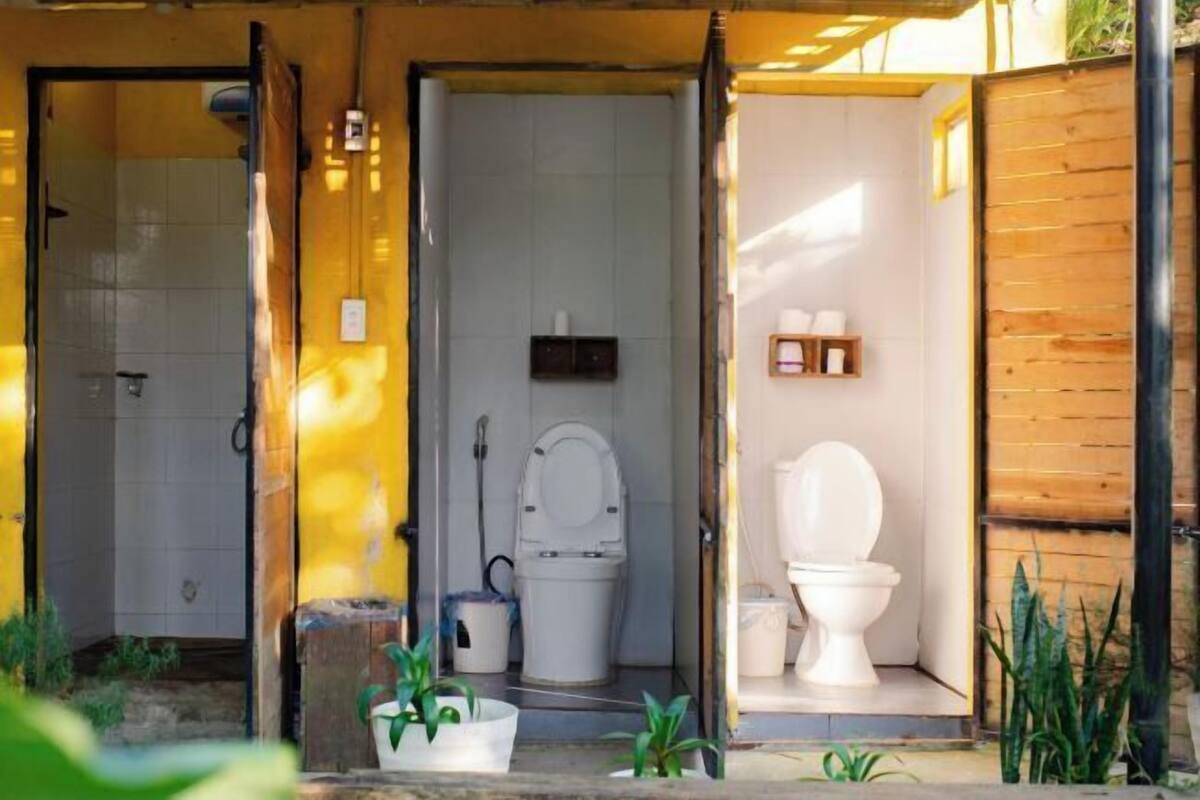 Une petite salle de bain compacte, équipée d’une douche, de toilettes et d’un lavabo.