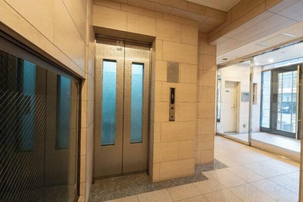 An elevator with a metallic finish, a glass door, and a control panel.