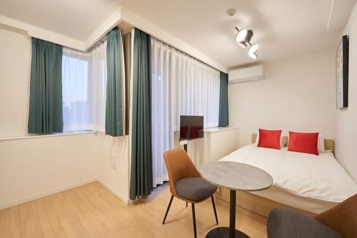 Ett hotellrum med en säng, ett litet bord, en stol och en tv.