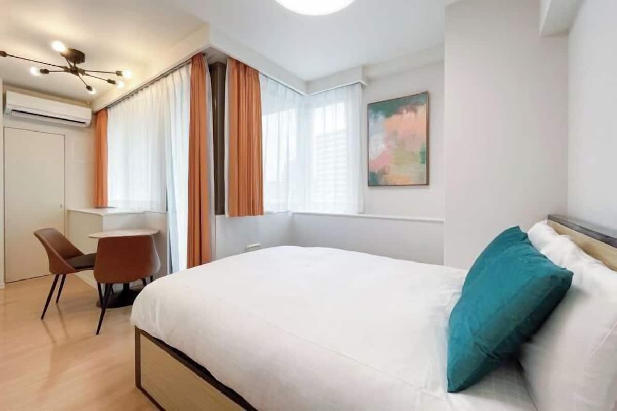 A modern hotel room with a large bed, a desk, and a chair.