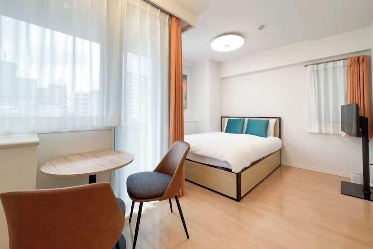 Ett hotellrum med en säng, en stol, ett litet bord och en tv.
