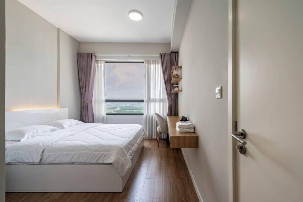 A modern hotel room with a large bed, a desk, and a view of the city.