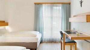A hotel room with a bed, a desk, and a chair.