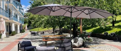 Een terras met een grote parasol, tuinmeubels en een pad van stenen.