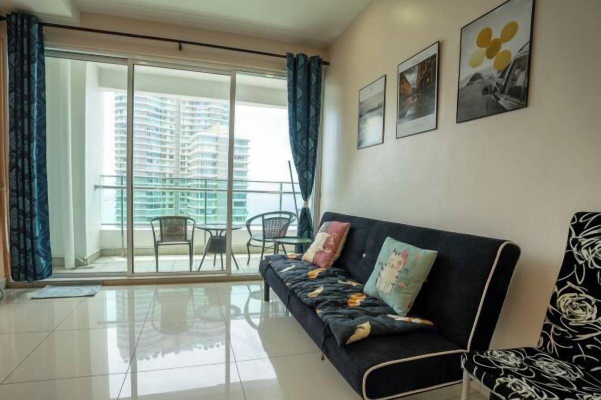 A modern living room with a sofa, chairs, and a balcony with a city view.