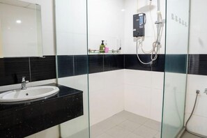 A modern bathroom with a glass-enclosed shower, a white sink, and a black countertop. - 2-bedroom condo with free parking on premises. (George Town)