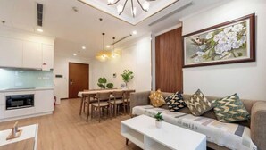 A modern living room with a sofa, coffee table, and dining area. - Gardenia Apartment Landmark (Ho Chi Minh City)