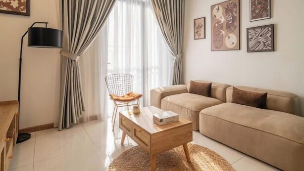 A living room with a sofa, a coffee table, a chair, and a lamp. - Gardenia Apartment Landmark (Ho Chi Minh City)