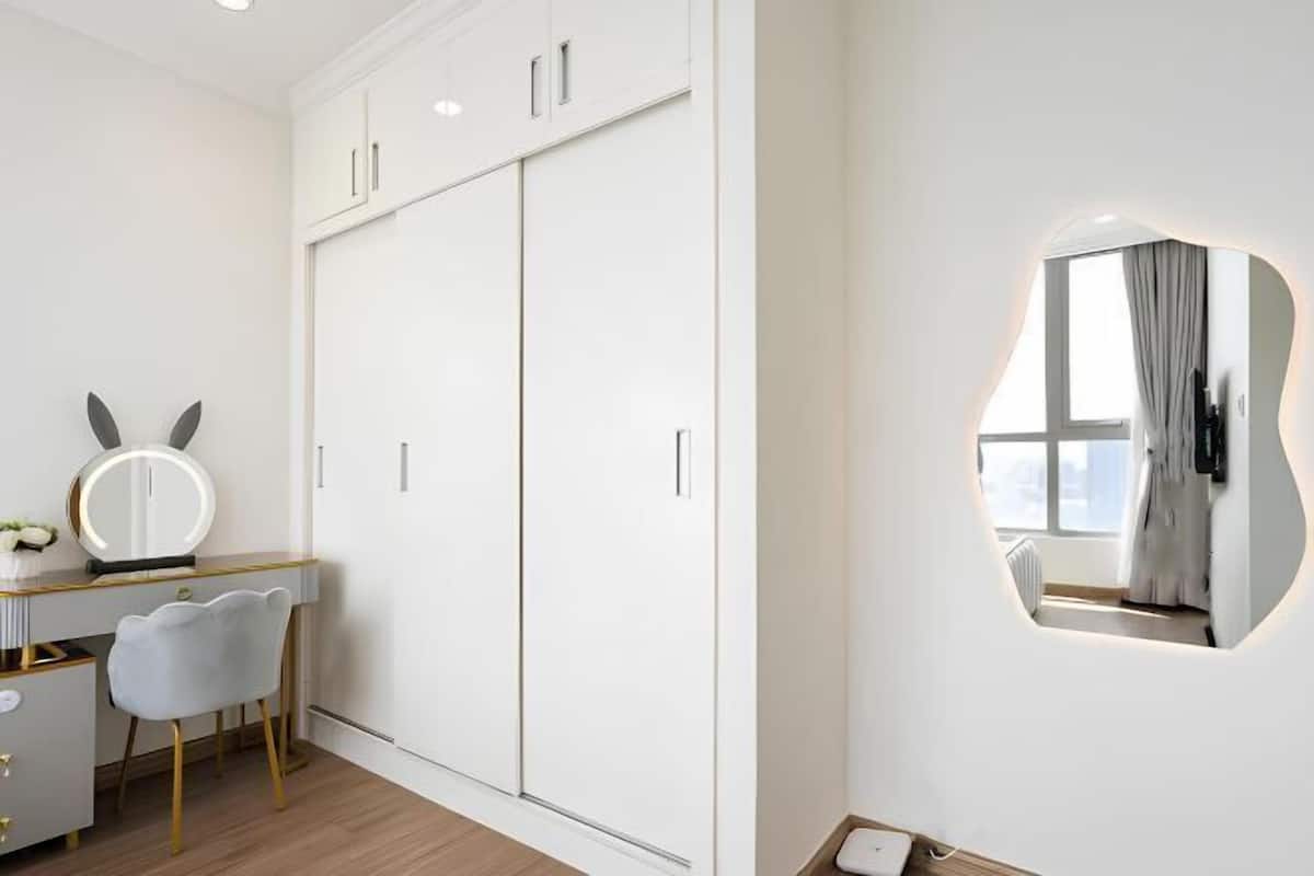 A modern bedroom with a large wardrobe, a vanity with a mirror, and a unique wall-mounted mirror.