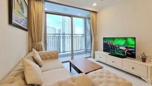 A modern living room with a large window, a sofa, a coffee table, and a TV. - Gardenia Apartment Landmark (Ho Chi Minh City)