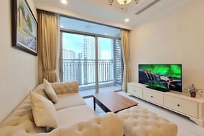 A modern living room with a large window, a sofa, a coffee table, and a TV.