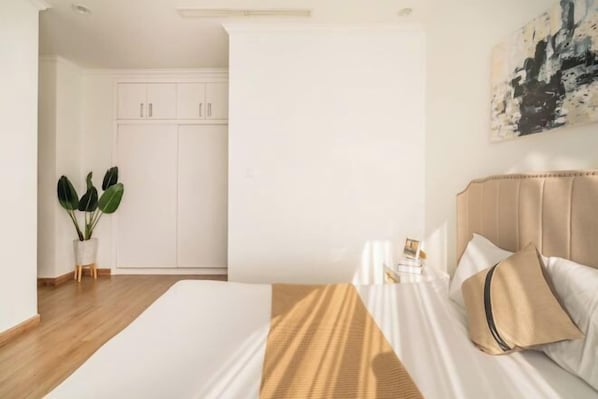 A bedroom with a bed, a nightstand, a potted plant, and a wardrobe.
