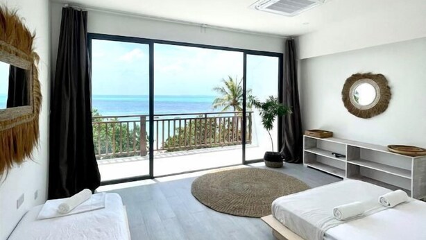 A bedroom with two beds, a large window with a view of the sea, a balcony, and a round mirror on the wall. - Samura Panorama Guest House (Thulusdhoo)
