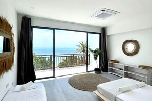 A bedroom with two beds, a large window with a view of the sea, a balcony, and a round mirror on the wall. - Samura Panorama Guest House (Thulusdhoo)