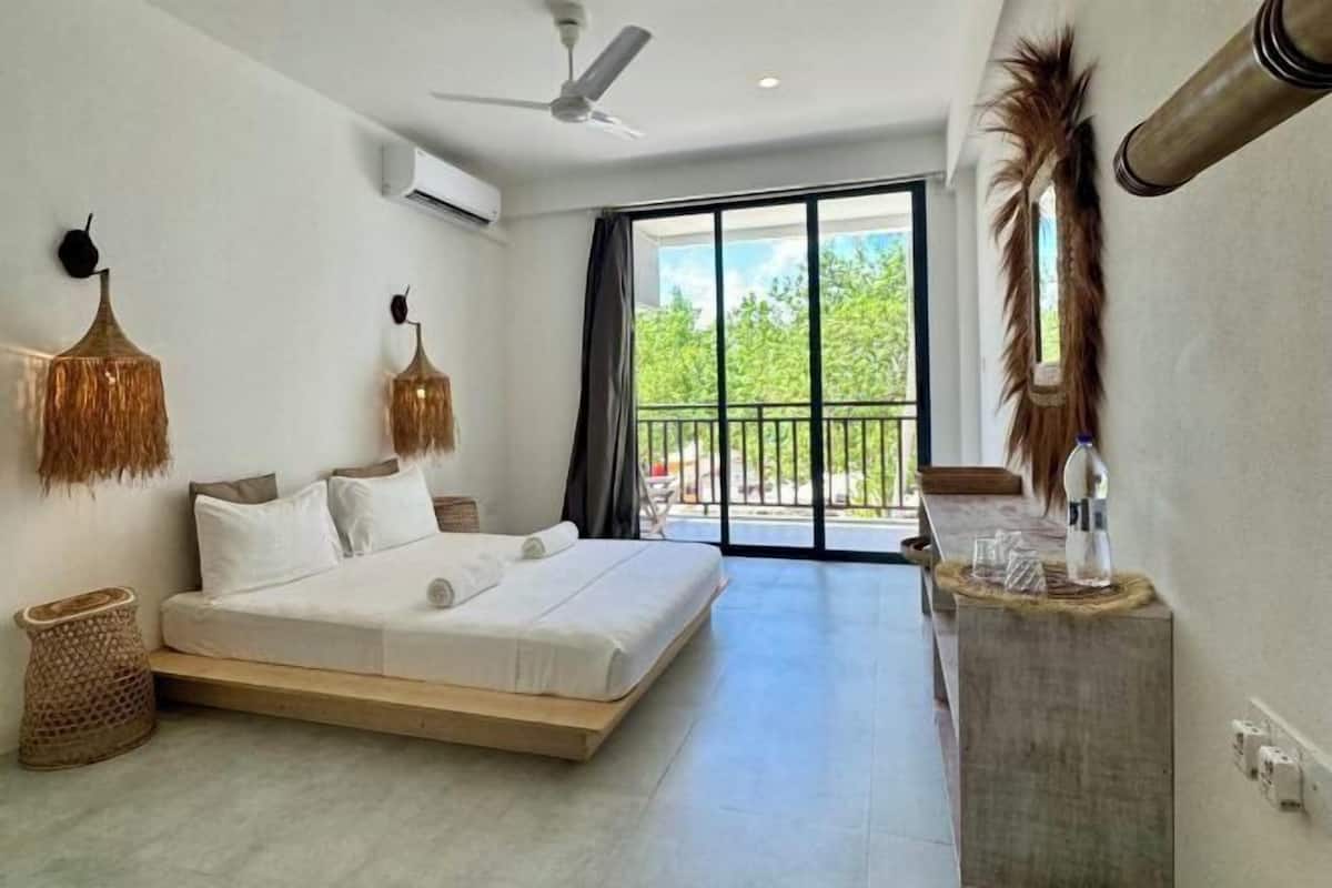 Ein modernes Schlafzimmer mit Bett, Deckenventilator und Blick ins Freie.