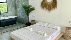 A modern bedroom with a large bed, a glass-enclosed bathroom, a potted plant, and a wall-mounted decorative item. - Samura Panorama Guest House (Thulusdhoo)