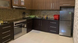 Eine moderne Küche mit dunklen Holzausführungen, einem Edelstahlkühlschrank und einer Granitarbeitsplatte.