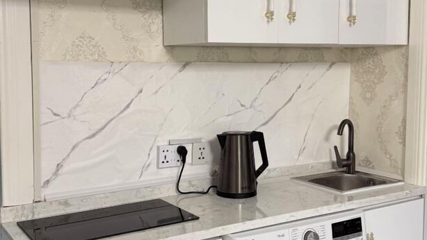 A kitchen with marble backsplash, a kettle, a sink, and a built-in oven. - UB Friends Hostel (Ulaanbaatar)