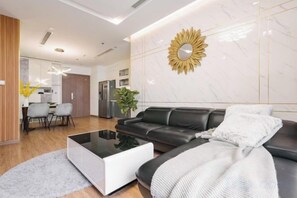 Un salon moderne avec un canapé en cuir noir, une table basse blanche et un élément décoratif mural.