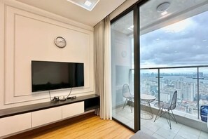 Un salón moderno con televisor de pantalla plana, un reloj y un balcón con vista a la ciudad.