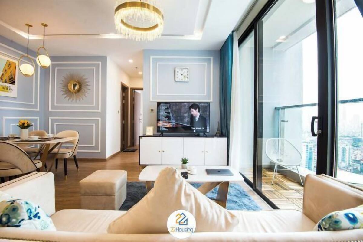 Un salon moderne comprenant un canapé, un coin repas et un téléviseur posé sur un meuble blanc.
