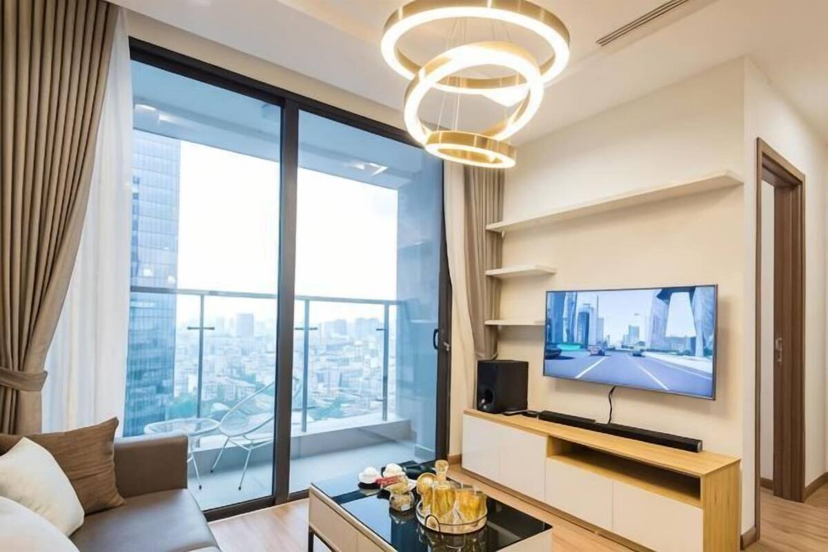 Un salon moderne doté d’une grande fenêtre, d’un téléviseur à écran plat, d’un canapé, d’une table basse et d’une table à manger.