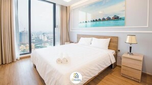 Een hotelkamer met een groot bed, een nachtkastje, een lamp en een schilderij van bungalows boven het water.