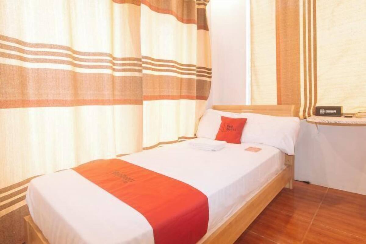 Une chambre d’hôtel avec un lit, des rideaux, une table de chevet et une petite table.