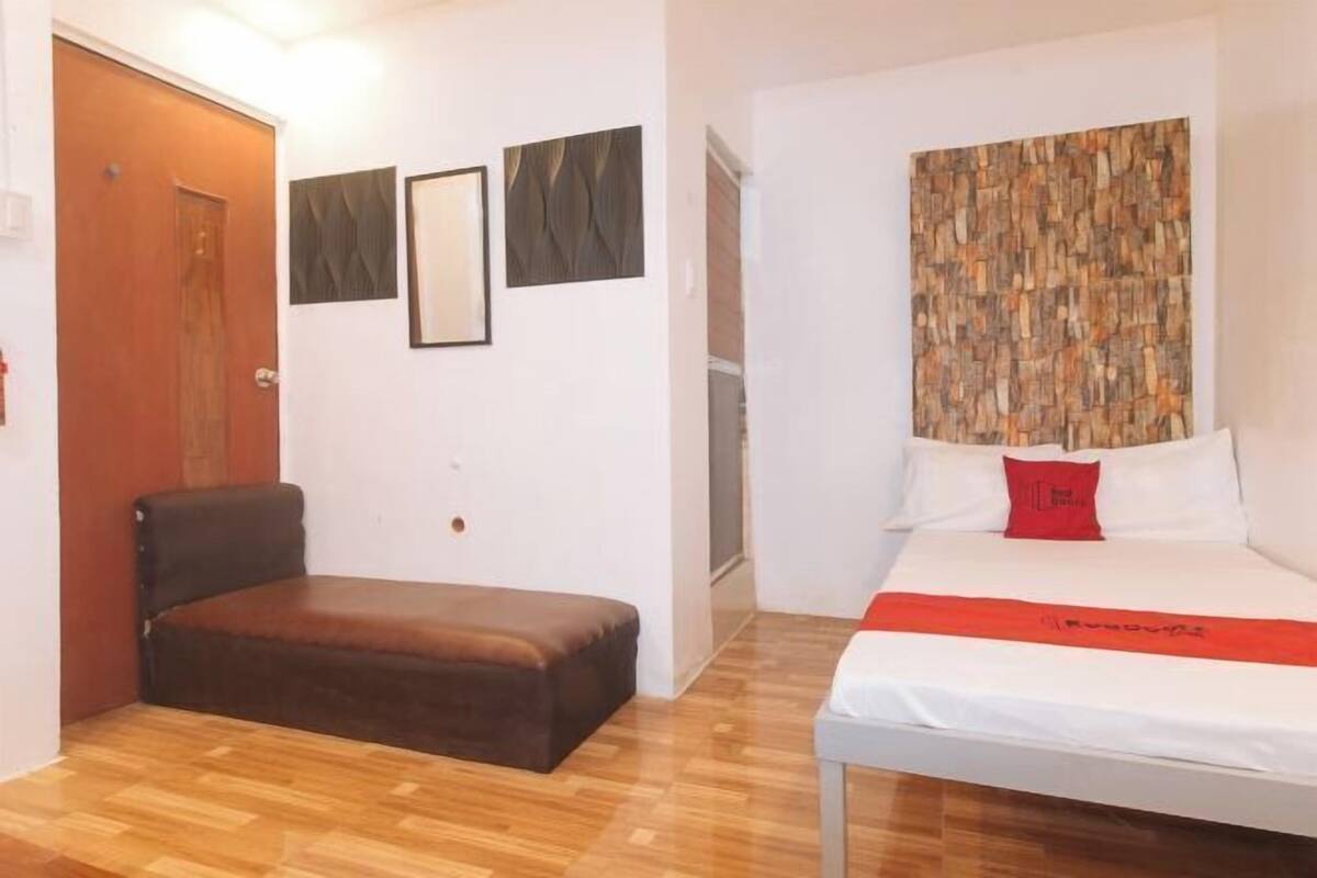 Une chambre d’hôtel avec un lit, un banc en cuir marron et un plancher en bois.