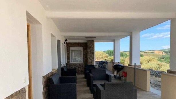 Un espace extérieur aménagé avec des sièges, abrité et doté de murs en pierre, offrant une vue sur le paysage.