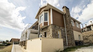A two-story house with a stone chimney, a balcony, and a small porch. - Land. Beautiful apartment. Villa de Gredos (Barajas)