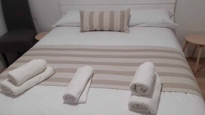 A neatly made bed with striped bedding and three rolled towels placed on it. - Land. Beautiful apartment. Villa de Gredos (Barajas)