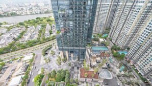 A high-rise building with a glass facade, surrounded by a plaza with trees and a parking area. - Vinhomes Central Park - PHAN DANG Residences (Ho Chi Minh City)