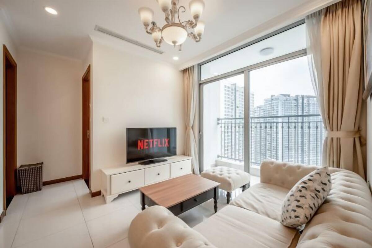A modern living room with a television displaying 'NETFLIX,' a sofa, a coffee table, and a large window with a city view.