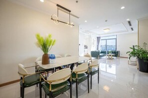 A modern dining area with a white table, green and white chairs, and a potted plant. - Vinhomes Central Park - PHAN DANG Residences (Ho Chi Minh City)