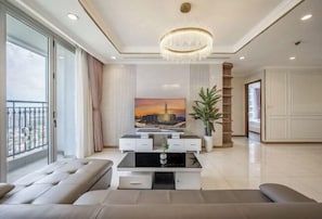 Un soggiorno moderno con una grande TV, un lampadario e un balcone.