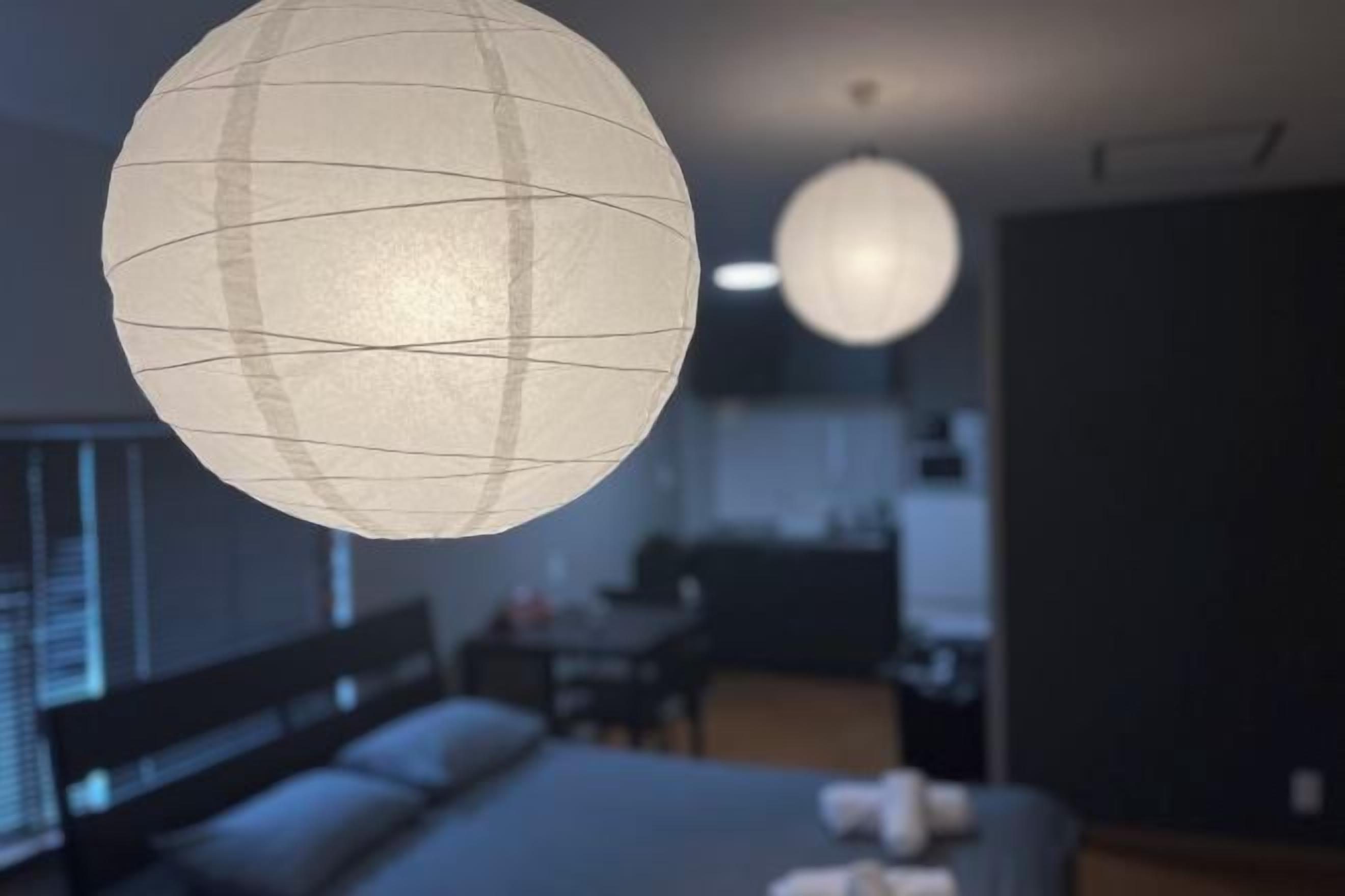 A room with a bed, a desk, and a hanging spherical light fixture.